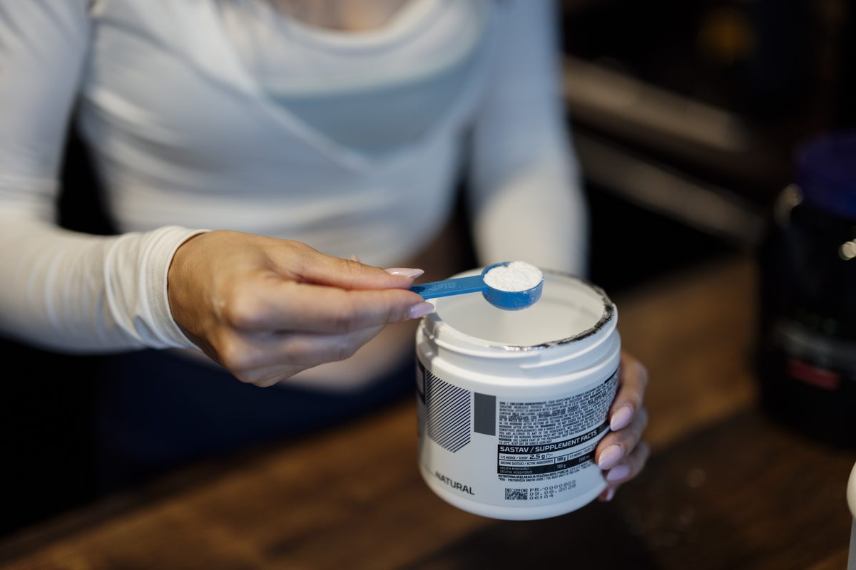 User measures a scoop of protein powder from a container in a kitchen